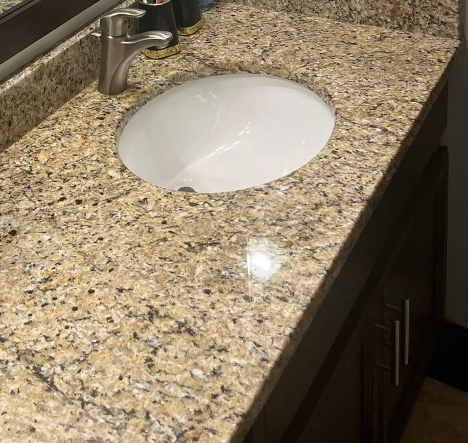 A clean granite bathroom counter with a white basin and brushed nickel faucet, the stone polished to a shine.